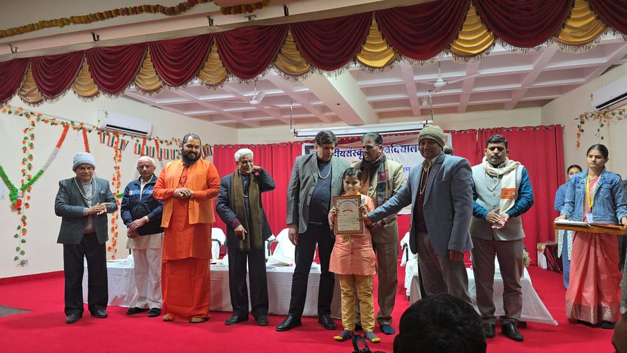 Vrishvardhan Sharma receiving his certificate on stage from a row of scholars and officials at Central Sanskrit University, Jaipur.