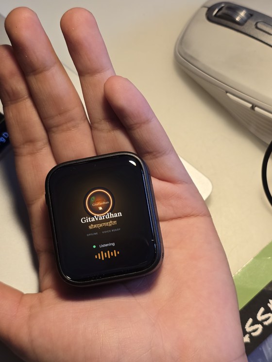 The touchscreen GitaVardhan device resting in an open palm, its screen reading GitaVardhan, offline, voice ready, and Listening.