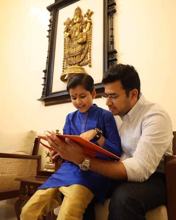 Vrishvardhan Sharma sitting with Shri Tejasvi Surya, the two of them reading from a bound handwritten volume.